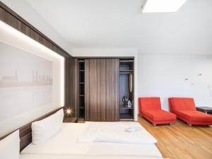 a bedroom with a bed and two red chairs at sevenDays Hotel BoardingHouse in Heidelberg