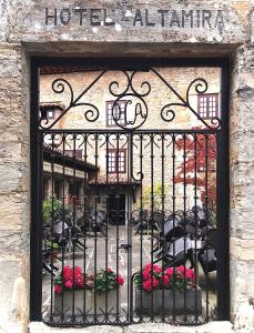 una puerta de hierro forjado con flores, mesas y sillas en Hotel Altamira, en Santillana del Mar