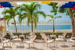 eine Terrasse mit Stühlen, einem Tisch und Palmen in der Unterkunft Santorini Hotel Boutique in Santa Marta