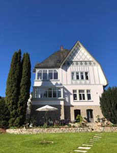 une grande maison blanche avec un parasol dans la cour dans l'établissement Villa Rosa - Sky, à Detmold