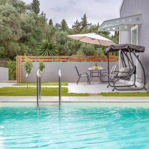 Summer Moments Pool Villa في Evropoúloi: مسبح بطاولة ومظلة