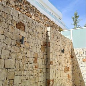 un mur en pierre avec un bâtiment derrière dans l'établissement SUITE CALA PAURA, à Polignano a Mare