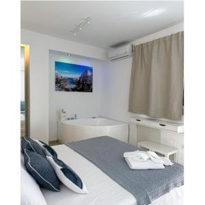 a white bedroom with a bed and a bath tub at SUITE CALA PAURA in Polignano a Mare