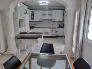 une cuisine avec des placards blancs et une table en verre dans l'établissement Villa Noelia Benalmadena, à Benalmádena