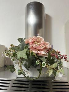 a vase with a pink rose on a table at Lūǧārah - elegante loft in centro storico in Lucera