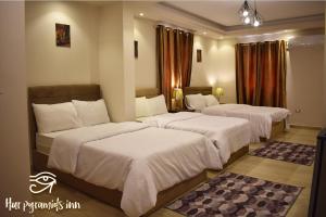 2 Betten in einem Hotelzimmer mit weißer Bettwäsche in der Unterkunft Hur Pyramids Inn in Kairo