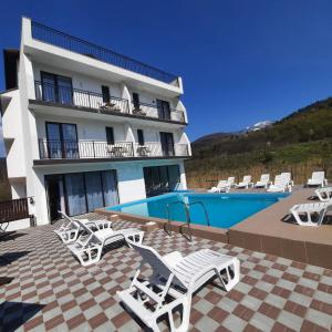 un hotel con piscina y tumbonas blancas en Andrana, en Caciulata