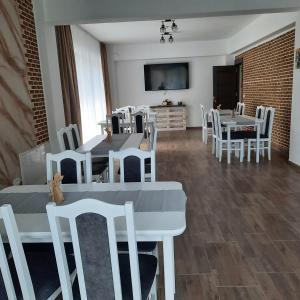 une salle à manger avec des tables et des chaises blanches dans l'établissement Andrana, à Căciulata