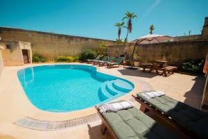 a swimming pool with chairs and a table and an umbrella at Razzett Ziffa in Victoria