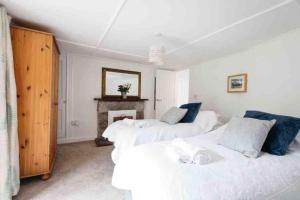 2 camas en una habitación blanca con chimenea en Spacious flat St Ives former farmhouse, parking, en St Ives