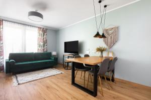 uma sala de estar com uma mesa e um sofá verde em Mary&Arte Apartments Grzegórzecka 15 em Cracóvia