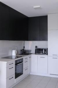 a kitchen with white appliances and black cabinets at D&A Apartments Obozowa in Warsaw