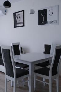 a white table and chairs with wine glasses on the wall at D&A Apartments Obozowa in Warsaw