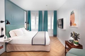 a bedroom with a large white bed with blue curtains at Hôtel Vendome Saint-Germain in Paris