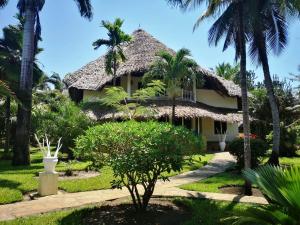 a house with palm trees in front of it at Aestus Villas Resort in Diani Beach