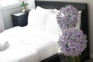 a vase of purple flowers on a table next to a bed at Immaculate 4-Bed House in Southampton in Southampton