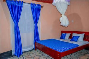 Jambo Afrika Resort في Emali: غرفة نوم بسرير والستائر زرقاء