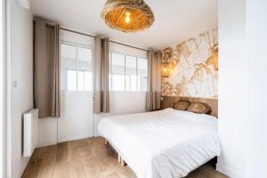 1 dormitorio con cama blanca y lámpara de araña en Rimini - Face mer La Baule, en La Baule