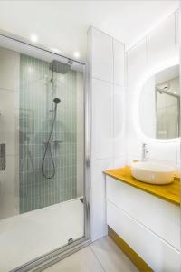 La salle de bains blanche est pourvue d'une douche et d'un lavabo. dans l'établissement Rimini - Face mer La Baule, à La Baule
