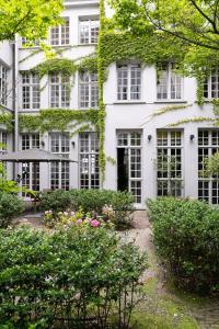 - un bâtiment blanc avec des fenêtres et des fleurs devant dans l'établissement Small Luxury Hotel De Witte Lelie, à Anvers