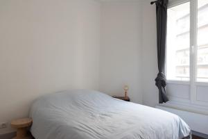 ein weißes Bett in einem Zimmer mit Fenster in der Unterkunft Charming love nest near Montmartre in Paris