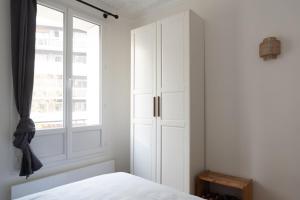 ein Schlafzimmer mit einem weißen Schrank und einem Fenster in der Unterkunft Charming love nest near Montmartre in Paris