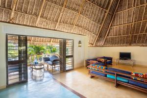 een woonkamer met een groot rieten dak bij Aestus Villas Resort in Diani Beach