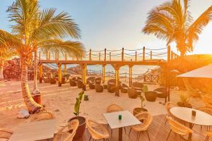 ein Restaurant am Strand mit Stühlen, Tischen und Palmen in der Unterkunft Casa Kaliste in Puerto Calero