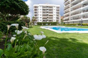 a garden with white flowers and a swimming pool at Sunny Apartment Alva Park in Lloret de Mar