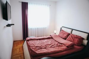 Un dormitorio con una cama con sábanas rojas y una ventana en Apartment Golden - 2BR with Parking, Prime Location, en Pristina