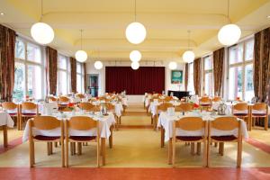 un salón de banquetes con mesas, sillas y ventanas en Hotel Morgenland, en Berlín