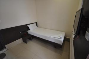 a small white bed in a room with a tv at Vijey Hotels in Tiruchirappalli