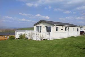 a white house with a white fence in a yard at Bay View Lodge, Brynowen in Borth