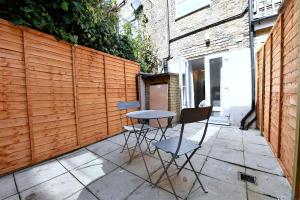 a patio with two chairs and a table in front of a fence at Stylish Studios by Luxestays Fulham in London