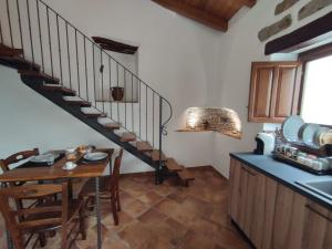 une cuisine avec une table et un escalier en colimaçon dans l'établissement La Corte Dei Baroni, à Loceri