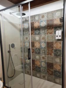 ducha con puerta de cristal y azulejos en la pared en La Corte Dei Baroni, en Loceri