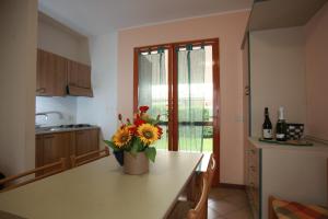 a kitchen with a table with a vase of flowers on it at Terraced house with garden and porch in Rosolina Mare