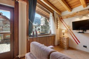 a living room with a couch and a large window at La Casetta di La Thuile in La Thuile