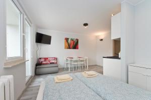 Cette chambre blanche comprend un lit et une table. dans l'établissement YOURAPART NORWIDA, à Gdynia