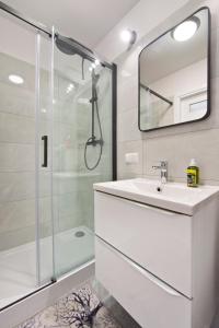 a white bathroom with a sink and a shower at YOURAPART NORWIDA in Gdynia