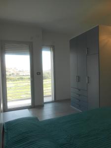 a bedroom with a bed and two large windows at Residence L'Ancora in Posada