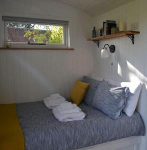 een slaapkamer met een bed met handdoeken erop bij The Nutbourne Hut - shepherd's hut - pint-sized luxury in Hambrook