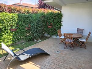 a patio with chairs and a table and a plant at Appartamento a Forte dei Marmi con giardino e 2 posti auto in Querceta