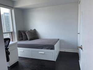 um pequeno quarto com uma cama e uma janela em TORONTO SKYLINE VIEW CONDO LIBERTY VILLAGE (Private Room & Bath) em Toronto