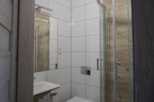 uma casa de banho branca com um chuveiro e um lavatório. em Hotel Pod Brzozą em Strzelce Opolskie