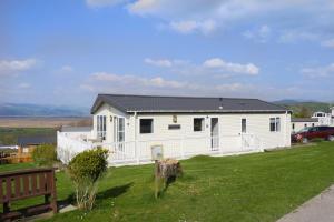 a white house on a green lawn with a car at Bay View Lodge, Brynowen in Borth