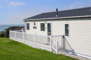 a white house with a white fence in front of it at Bay View Lodge, Brynowen in Borth