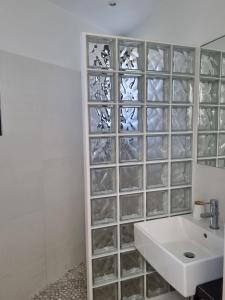 a bathroom with a white sink and a glass block wall at Malouins 2307 villa in Les Issambres