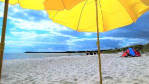 a yellow umbrella on a beach with a tent at Strandhaus Lobbe 45481 in Lobbe