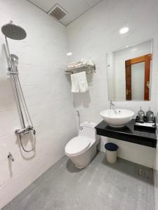 a white bathroom with a toilet and a sink at Hotel Hoàng My in Pleiku